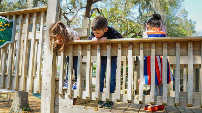 Three children playing on a jungle gym