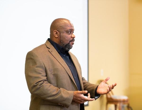 Male professor teaching in front of a classroom.